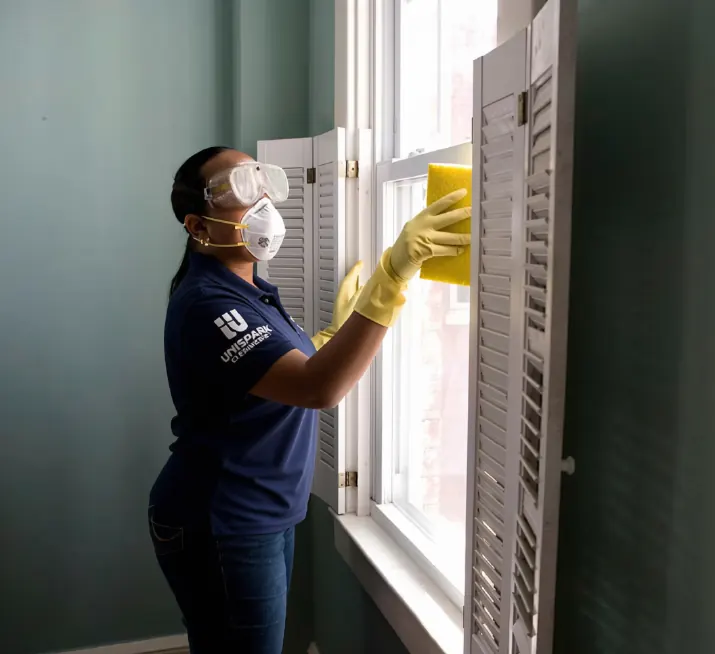 UniSpark cleaner in protective gloves cleaning shutters during a move-out clean